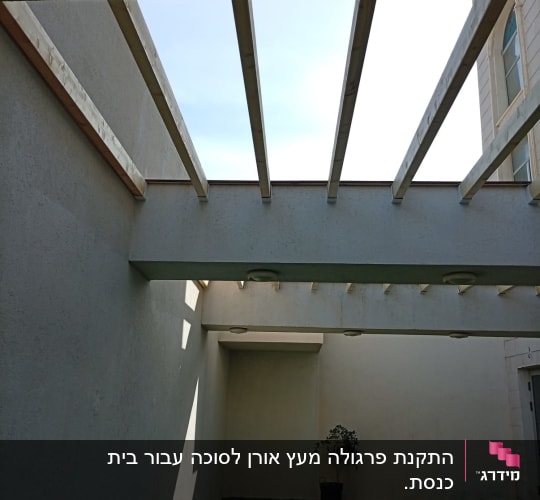 קורות עץ על תקרה בחצר עם דשא ועציץ